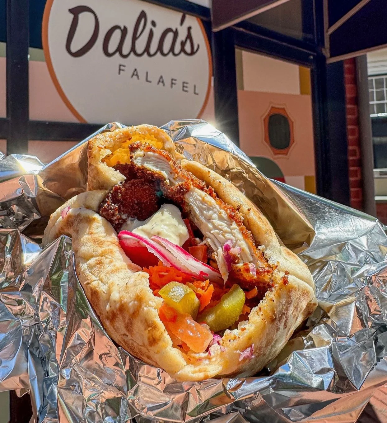 Stuffed pita with crispy chicken, falafel, pickles and tahini